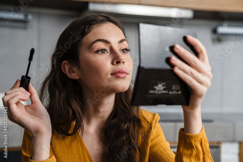 Fotografie Smiling young brunette woman doing makeup