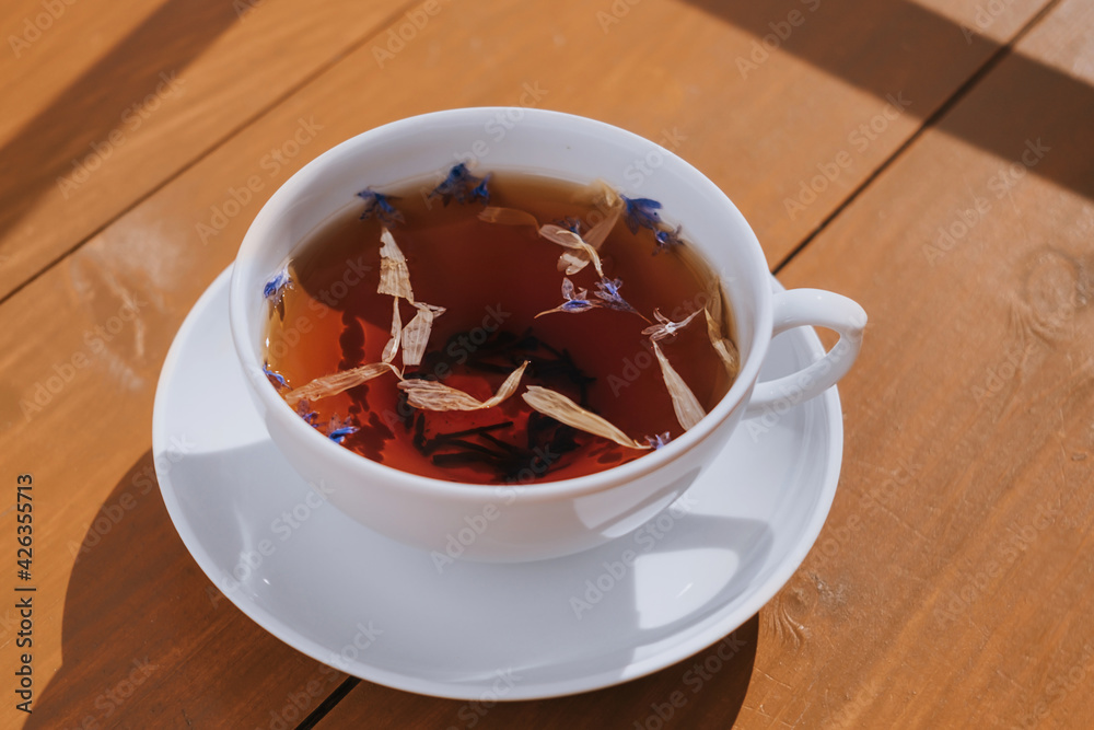 White cup of herbal tea with a saucer. Bright sunlight. The concept of tea drinking, healthy drinks. White cup of herbal tea with a saucer. Bright sunlight. The concept of tea drinking, healthy drinks.