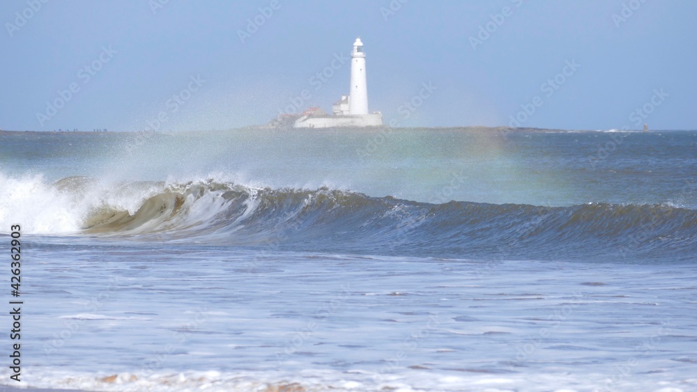 Wavebow / rainbow in waves with Lighthouse behind 