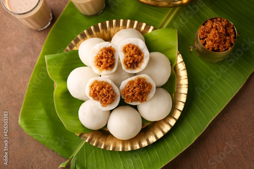Kozhukatta Pidi in golden plate Indian milk tea Kerala tea time snack steamed food sweet modak rice dumpling Ganesh Festival India sweet food stuffed grated coconut jaggery christian food Palm sunday 