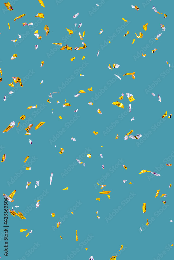 Golden silver sparkling confetti isolated on turquoise. Holiday effect
