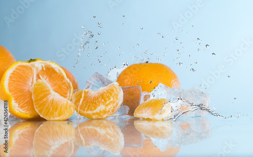 tangerines on a blue background, water splash, crushed ice, ice cubes