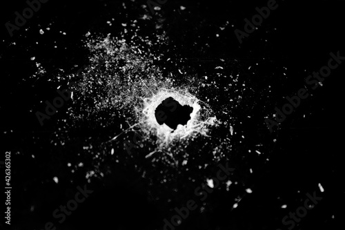Cracked glass, hole and crack on a black background.Broken glass. Concept for copy and edit.