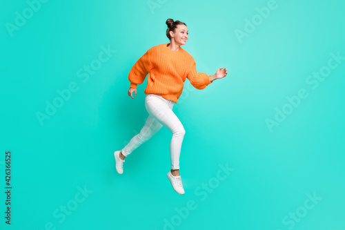 Full size photo of young attractive lovely smiling girl running in air looking copyspace isolated on teal color background