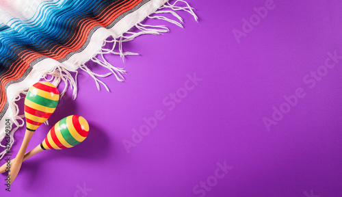 Cinco de Mayo holiday background made from maracas, mexican blanket stripes or poncho serape on purple background.