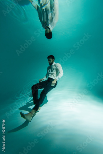 Arabian businessman swimming near bottom of swimming pool