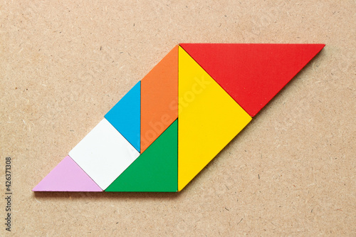 Color tangram puzzle in parallelogram shape on wood background photo
