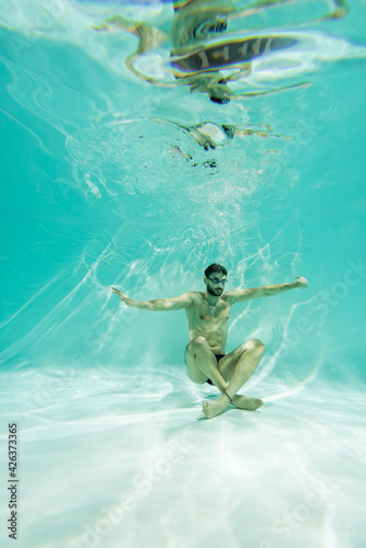 Muslim swimmer in goggles swimming near bottom of pool