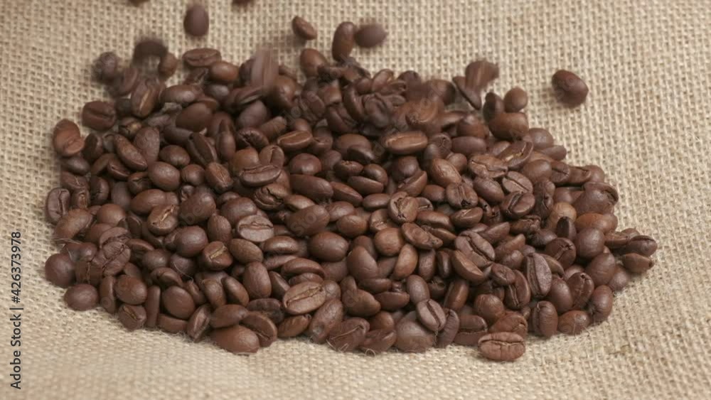 Coffee beans falling on jute background at slow motion. Organic agriculture, harvest Coffee beans falling on jute background at slow motion. Organic agriculture, harvest