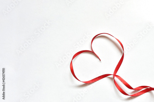 heart made of thin red satin ribbon laid out on a white background