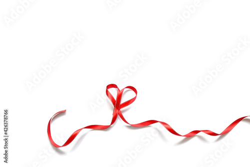 narrow red satin ribbon folded into a heart on a white background
