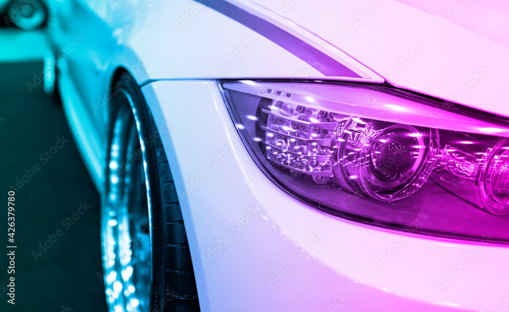 Headlight of a modern sport car.The front lights of the car. Modern Car exterior details in pink and blue tones