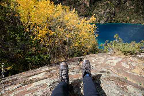 Hiker sit on cliff edge facing the beautiful high altitude lake