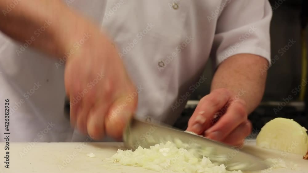 A male professional chef's hands im the final stages of chopping an onion in the kitchen of a hotel or restaurant. A male professional chef's hands im the final stages of chopping an onion in the kitchen of a hotel or restaurant.