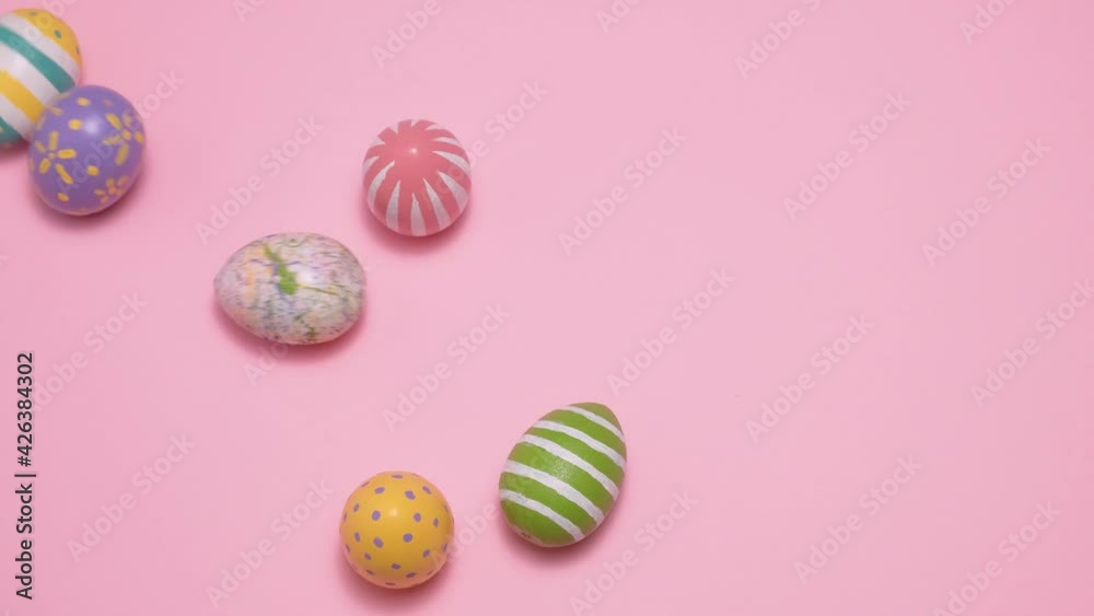 Video of Happy Easter. Colorful painted Easter eggs roll and knock each other on a pink background. Video of Happy Easter. Colorful painted Easter eggs roll and knock each other on a pink background.