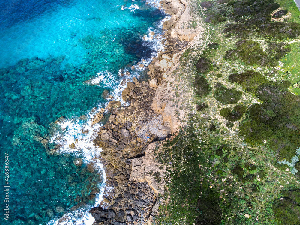 Aerial view of green shore and blue sea in Alghero