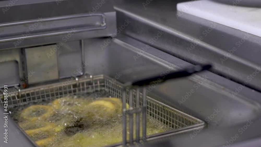 Close up of a fries cooking in a deep fat fryer in a professional kitchen of a hotel or restaurant. Close up of a fries cooking in a deep fat fryer in a professional kitchen of a hotel or restaurant.