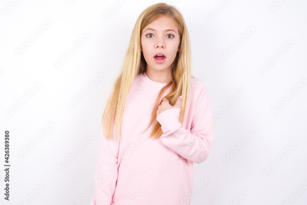 beautiful caucasian little girl wearing pink hoodie over white background being in stupor shocked, has astonished expression pointing at oneself with finger saying: Who me? beautiful caucasian little girl wearing pink hoodie over white background being in stupor shocked, has astonished expression pointing at oneself with finger saying: Who me?