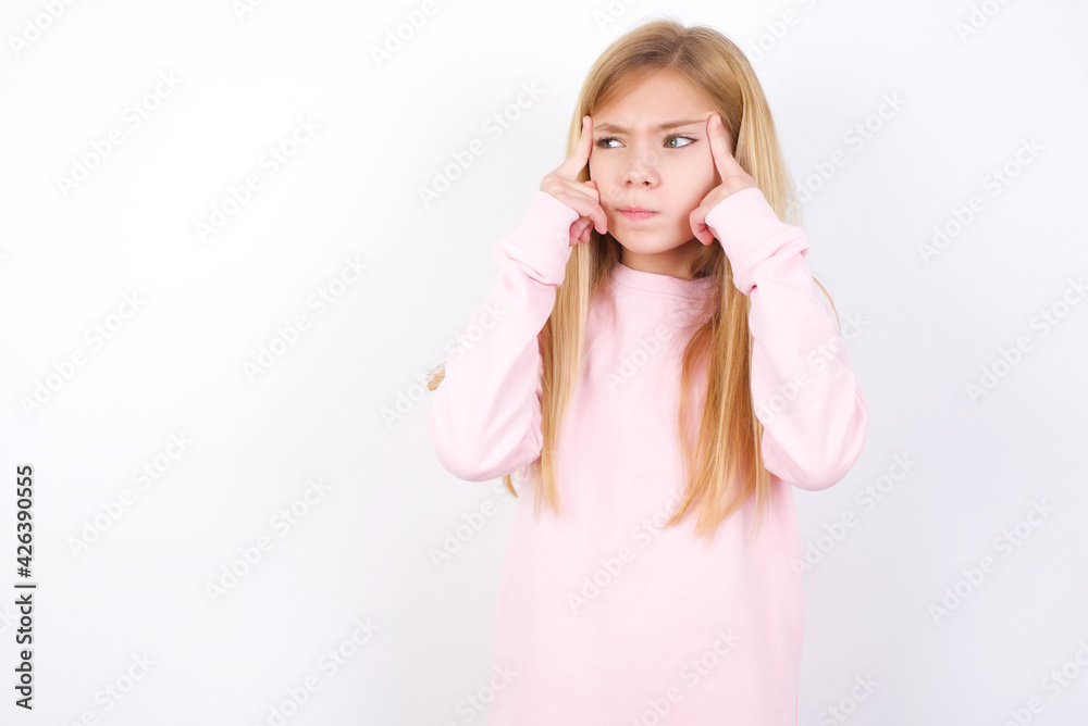 beautiful caucasian little girl wearing pink hoodie over white background with thoughtful expression, looks away, keeps hand near face, thinks about something pleasant. beautiful caucasian little girl wearing pink hoodie over white background with thoughtful expression, looks away, keeps hand near face, thinks about something pleasant.