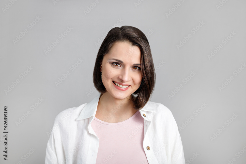 Portrait of smiling young brunette multiethnic woman in pink tank and white shirt