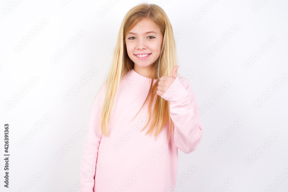 beautiful caucasian little girl wearing pink hoodie over white background giving thumb up gesture, good Job! Positive human emotion facial expression body language. beautiful caucasian little girl wearing pink hoodie over white background giving thumb up gesture, good Job! Positive human emotion facial expression body language.