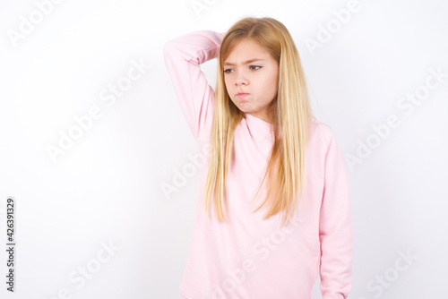 beautiful caucasian little girl wearing pink hoodie over white background saying  Oops  what did I do  Holding hand on head with frightened and regret expression.