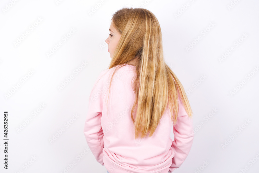 The back view of beautiful caucasian little girl wearing pink hoodie over white background Studio Shoot. The back view of beautiful caucasian little girl wearing pink hoodie over white background Studio Shoot.