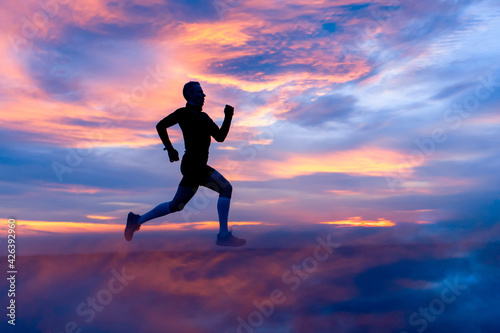 Running athlete silhouette on fiery clouds background