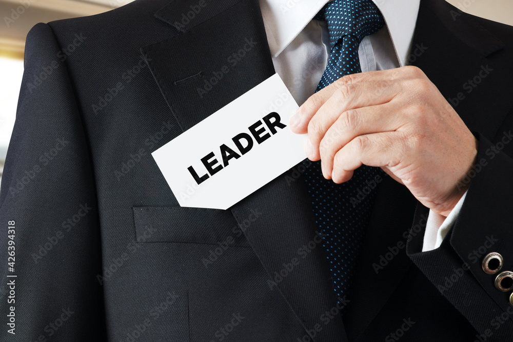 Businessman takes out a business card from his pocket with the word leader. Business leadership Businessman takes out a business card from his pocket with the word leader. Business leadership