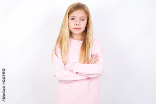 Picture of angry beautiful caucasian little girl wearing pink hoodie over white background looking camera.