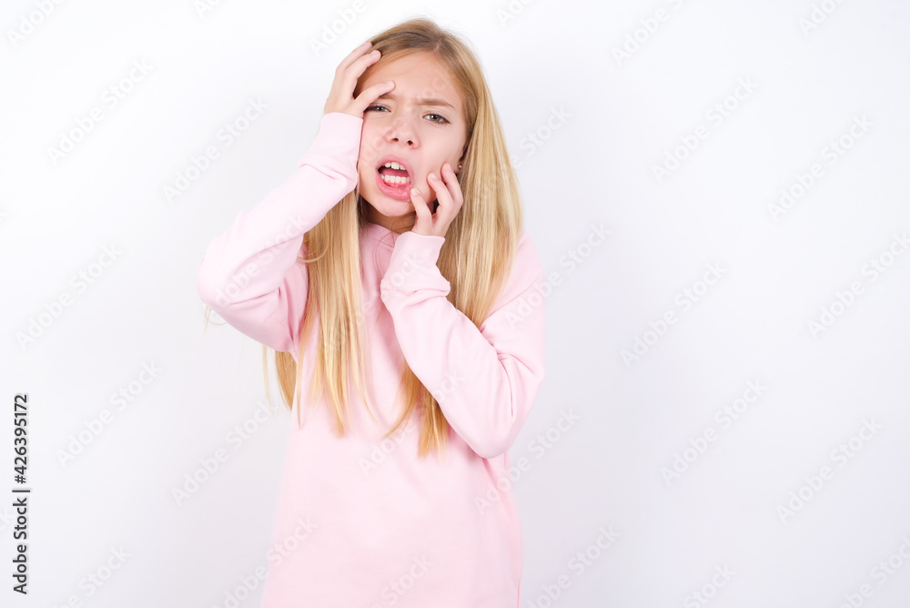 Young gloomy beautiful caucasian little girl wearing pink hoodie over white background, hiding face with hands pouting and crying, standing upset and depressed complaining about job problem. Young gloomy beautiful caucasian little girl wearing pink hoodie over white background, hiding face with hands pouting and crying, standing upset and depressed complaining about job problem.