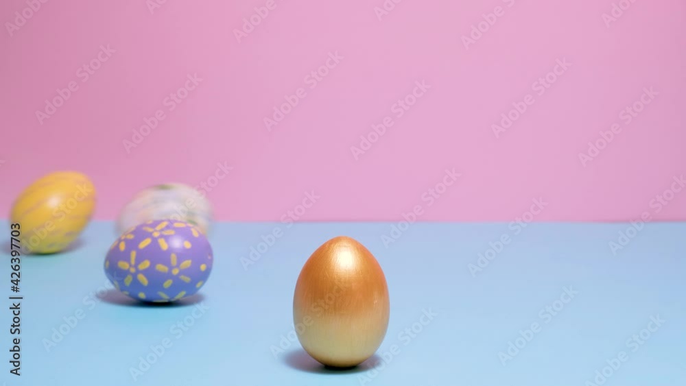 Video of Happy Easter. Colorful painted Easter eggs roll and knock each other on a blue and pink background. Hello spring and easter concept. 4k video. Video of Happy Easter. Colorful painted Easter eggs roll and knock each other on a blue and pink background. Hello spring and easter concept. 4k video.