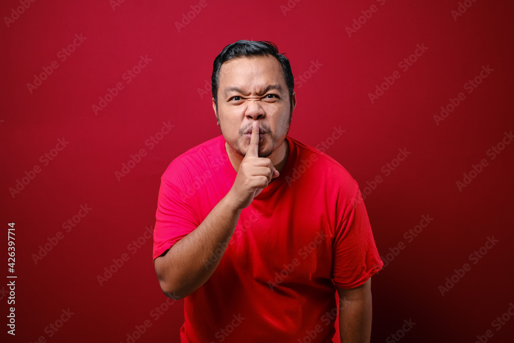 Serious strict man holding finger near lips, showing shh gesture asking to keep silence and be quite