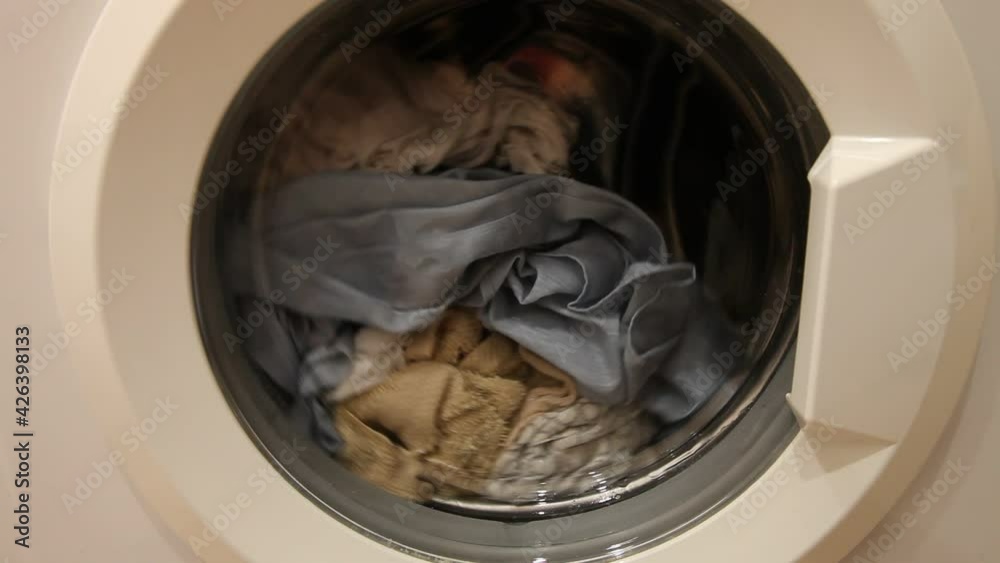 A clothing mix rotation leveling in front loaded wash machine can closeup, household washing A clothing mix rotation leveling in front loaded wash machine can closeup, household washing