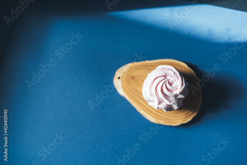 Fresh marshmallow on a blue background. Zephyr, meringue. The concept of home-cooked food. Minimalism, top view, flat lay, copyspace.