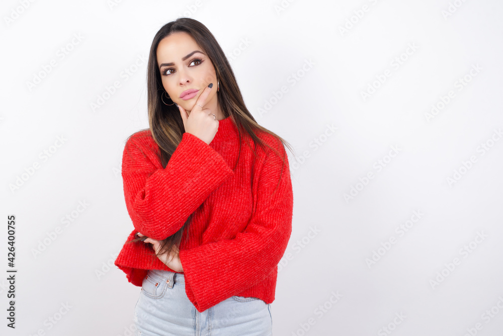 young beautiful brunette woman wearing red knitted sweater over white wall, dancing and listening music with headphones. young beautiful brunette woman wearing red knitted sweater over white wall, dancing and listening music with headphones.