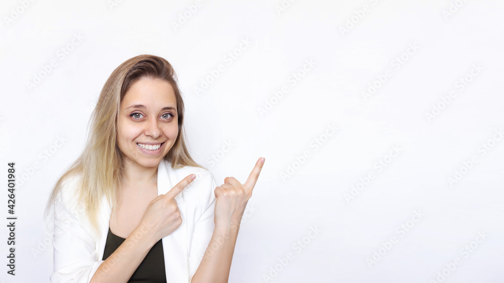 A young caucasian happy smiling successful blonde woman in a white jacket indicate copy empty blank space for text with two hands isolated on white background. Businesswoman presenting product. Banner A young caucasian happy smiling successful blonde woman in a white jacket indicate copy empty blank space for text with two hands isolated on white background. Businesswoman presenting product. Banner