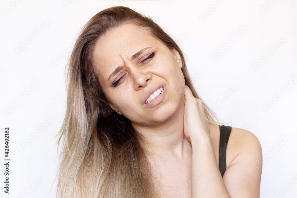 A young beautiful caucasian blonde woman with a neck pain holding her neck isolated on white background. The girl suffers from an osteochondrosis
