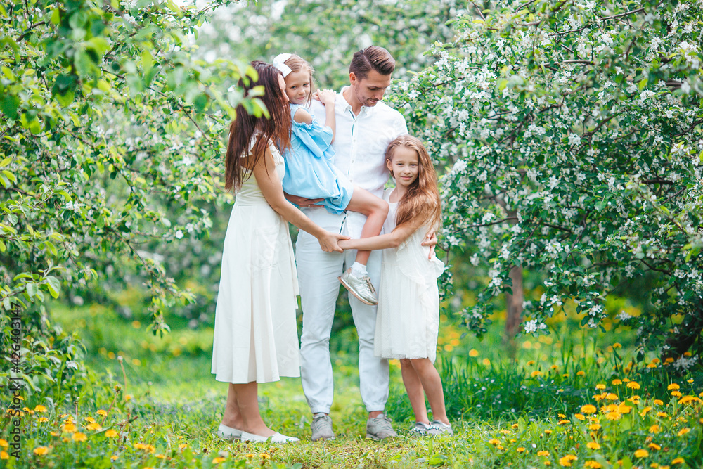Fototapeta premium Adorable family in blooming cherry garden on beautiful spring day