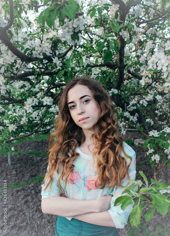 Close-up portrait of a girl with long hair among the branches of a blossoming apple tree Close-up portrait of a girl with long hair among the branches of a blossoming apple tree
