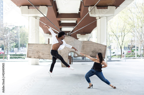 Caucasian woman and African American man dancing having fun in the city center. Space for text.