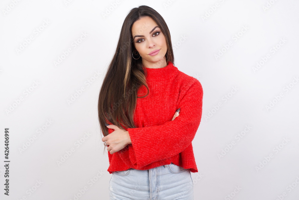 Picture of angry young beautiful brunette woman wearing red knitted sweater over white wall looking camera. Picture of angry young beautiful brunette woman wearing red knitted sweater over white wall looking camera.