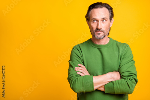 Photo of curious man folded hands look side empty space wear green sweater isolated yellow color background