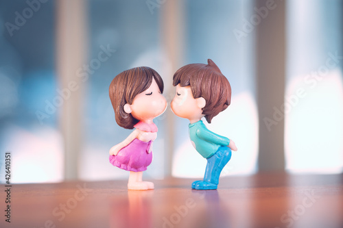 Miniature boy kiss girl with pink clock background using as family and Valentine's Day concept