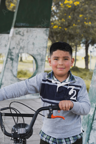 Boy walking with his bicycle.