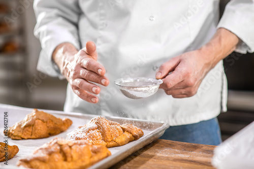 Obraz na plátne Male hands sprinkling confectionery with powdered sugar