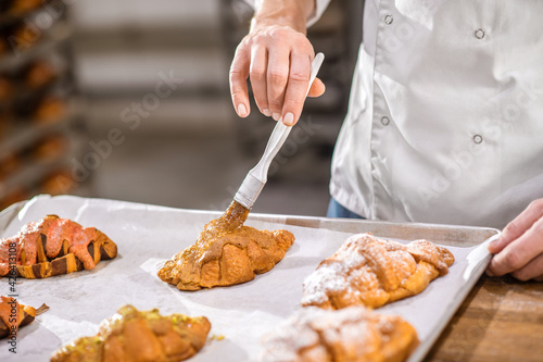 Male hand with brush touching croissant surface