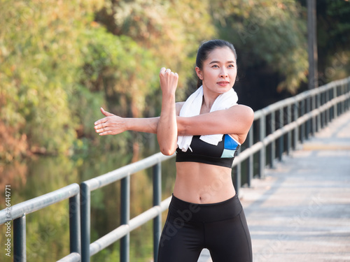 Portrait of beautiful Asian woman with a fit body in sportswear exercising outdoors workout before a fitness training session at the park in the morning.