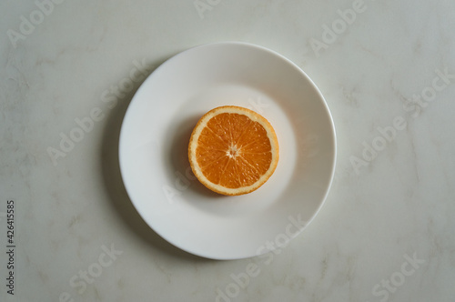 Big juicy ring of orange on white plate on white marble table