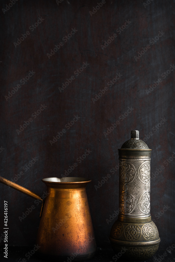 Traditional Turkish coffee and concept. Copper coffee pot. Cezve, vintage coffee grinder on a dark background.